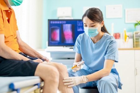 close up of asian female doctor make injection to male elderly senior patient in knee at hospital