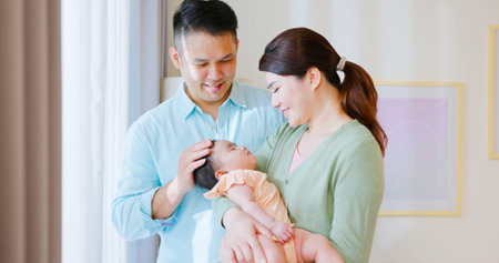 family time - Young man is standing by windows with his wife and sleeping child happily