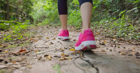 close up - feet in shoes of asian young woman backpacker is walking on mountain stone stairs through...