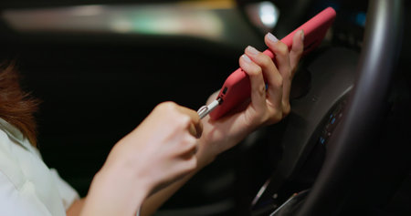 close up of asian businesswoman use smartphone charging cable to connect car at nightの写真素材