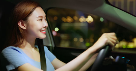 asian successful businesswoman is looking at city view while commuting in the cab at nightの写真素材