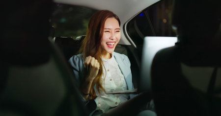 asian successful businesswoman is looking at city view while commuting in the cab at night