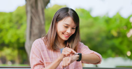 asian young woman has video chat with friends happily through smart phone in the park or campusの写真素材