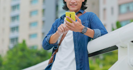 asian man walking on the street feeling upset using his smartphone