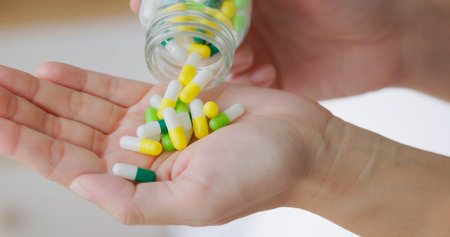 close up of hand asian woman pour capsule medicine out of bottle