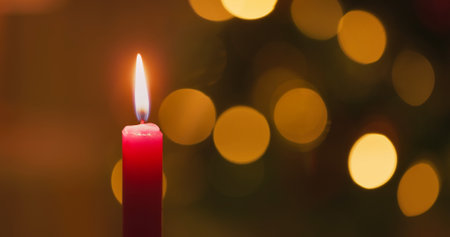 close up single red paraffin candle flame burning in front of blurred bokeh lights backgroundの写真素材