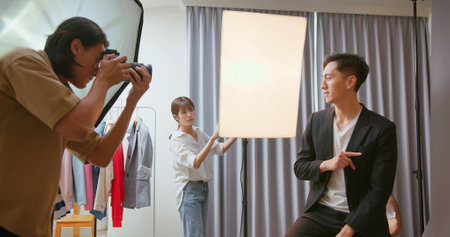 Male Asian photographer shooting photo with model and assistantの写真素材