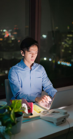 Asian business man sitting in office using laptop at work