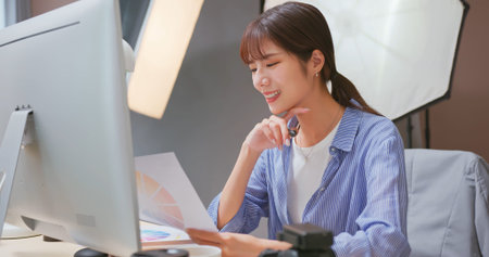 Female Asian photographer checking color of photo on screen
