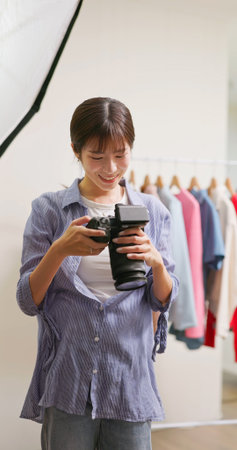Female Asian photographer checking results with camera