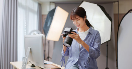 Female Asian photographer reviewing photo with camera shows satisfaction