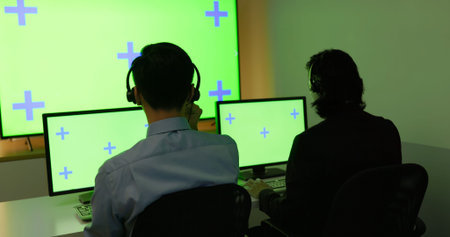 Rear view - Asian customer service operators working with green screen