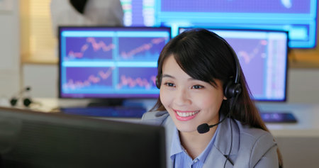 Asian female stock market analysts are working on customer service through computer and headsets in officeの写真素材