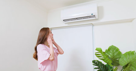 asian woman trying covering her ears is annoying and she is suffering noise from air conditioner at homeの写真素材