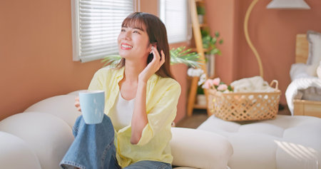 asian girl wear earbuds listen to the music happily and leisurely with a cup of coffee or teaの写真素材