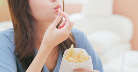 close up happy asian girl eat french fries and enjoy it a lot - unhealthy food makes people happy conflictsの写真素材