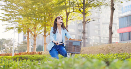 asian happy woman is riding a sharing bike commuting to work in the cityの写真素材