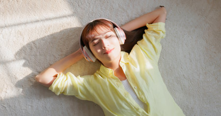 top-down view asian girl laying on floor wear headset listen to the music happily and leisurelyの写真素材