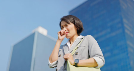 asian businessfemale is coughing due to the polluted air in cityの写真素材