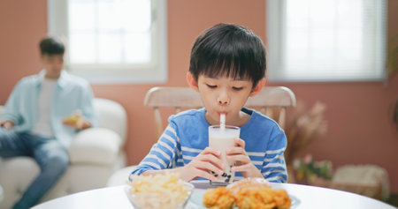 asian children eat unhealthy high calorie sugary junk food such as fried chicken french fries burgers bubble tea - father is scrolling his mobile with careless on the boyの写真素材