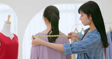 closeup asian professional female dress designer - she is helping her customer measuring her body...