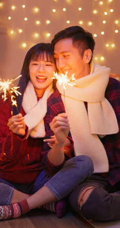 asian lovely young couple are having sparklers fireworks happily for the christmas celebration with...