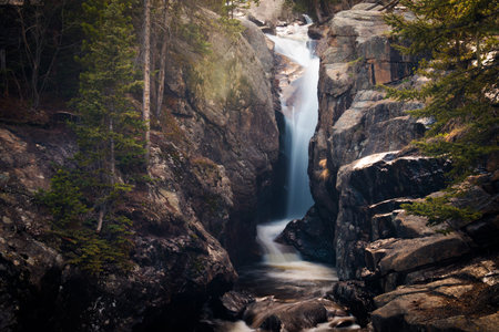 Landscape with waterfall flowing into a stony brook.