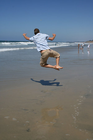 Man Jumping for joy on beachの写真素材
