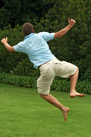 man jumping in air, clicking heels together with happinessの写真素材