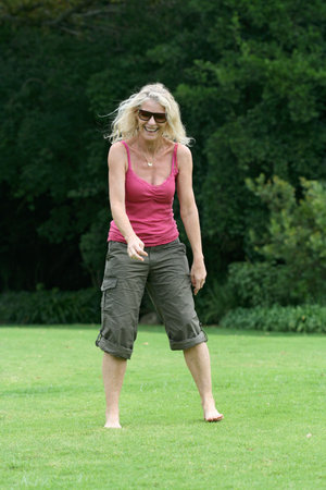 Healthy woman in her fifties laughing, standing on grass. See my other happy person jumping shots in my portfolio!の写真素材