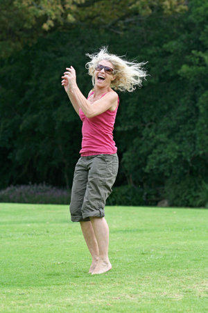 Healthy woman in her fifties jumping and laughing. See my other happy person jumping shots in my portfolio!の写真素材