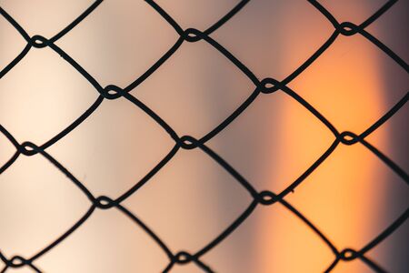 A wallpaper of the fence with an orange light in the backgroundの写真素材