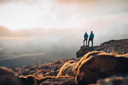 Couple travelers Man and Woman standing on cliff relaxing mountains and clouds aerial view Love and...