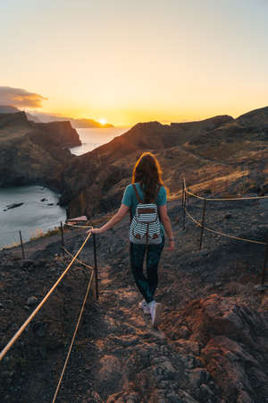 A solo female traveler enjoys colourful sunset on the coast. Summer lifestyle female photo. High quality photoの写真素材
