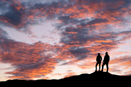 A silhouette of young adventurous couple watching the colourful sunset. High quality photoの写真素材