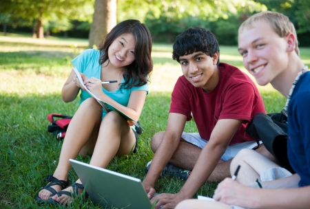 A group of three happy teenagers studying outsideの写真素材