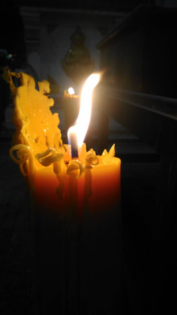 One candle flame light at night with bokeh on dark backgroundの写真素材