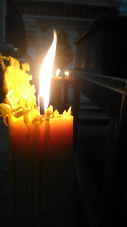 One candle flame light at night with bokeh on dark backgroundの写真素材