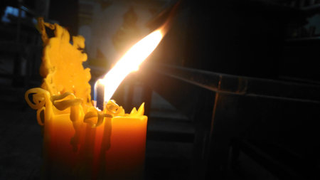 One candle flame light at night with bokeh on dark backgroundの写真素材