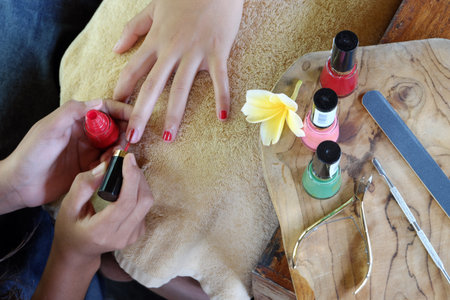 a woman do a nail polish with a red colourの写真素材