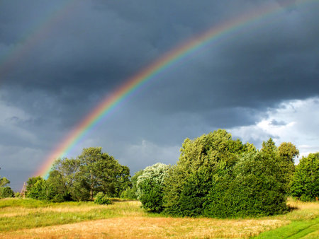 Rainbow in cloudy sky over rural landscape  の写真素材