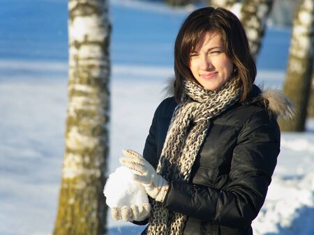 Young Woman With Snowball In Winter Landscapeの写真素材