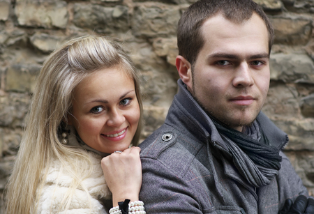 Young Woman Smiling From Behind Her Boyfriend Near Old Brick Wallの写真素材