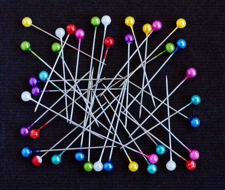 Multicolored pins lying over dark black backgroundの写真素材