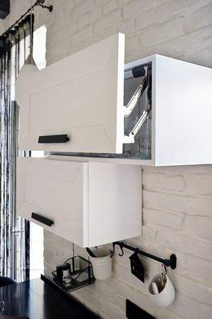 Ajar Opened White Kitchen Cabinet with Wineglasses on Shelfの写真素材