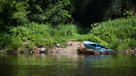 Two old rowing fishing boats moored on green summer beach on Neman River Grodno Belarusの写真素材