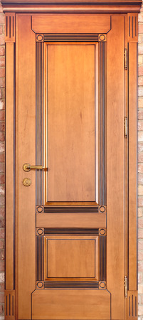 Wooden interior door of maple wood with brass handle and with geometric ornament on brick backgroundの写真素材