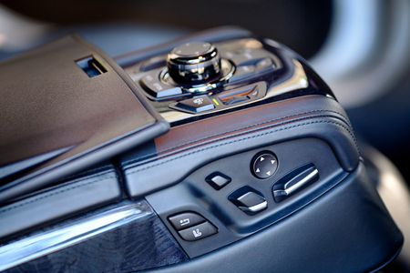 Control unit with electric seat adjustment and stereo media system for rear passengers in contemporary luxury car. Element of interior of expensive car armrest with electric seat adjustment and media system of wood and leather.の写真素材