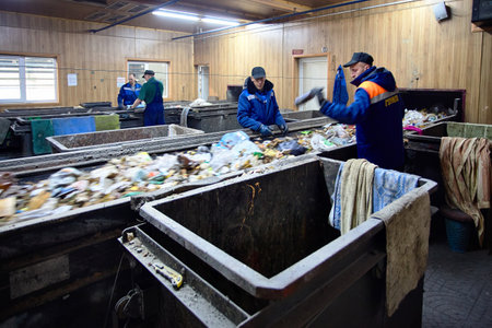 GRODNO, BELARUS - OCTOBER 2018: Four workers in uniform working at waste processing plant sorting recyclable materials from garbage on conveyor belt.のeditorial素材