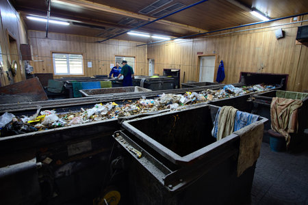 GRODNO, BELARUS - OCTOBER 2018: Two workers in uniform working at waste processing plant sorting recyclable materials from garbage on conveyor belt.のeditorial素材